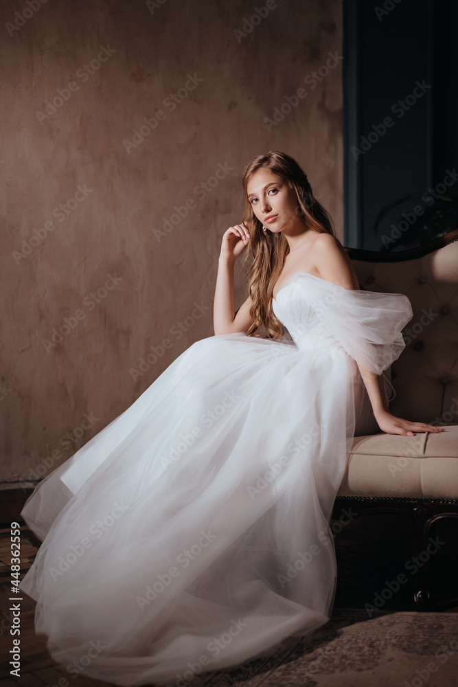 Beautiful brunette bride with light make-up in white dress  in an exquisite interior 