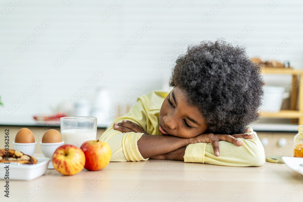 A little boy is sitting at the kitchen table leaning her face in her arms, concept for bullying, depression stress or frustration A little boy is sitting at the kitchen table leaning her face in her arms, concept for bullying, depression stress or frustration
