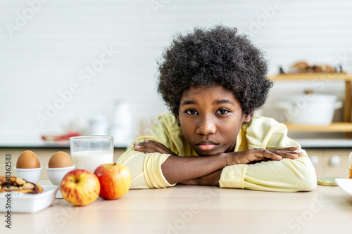 A little boy is sitting at the kitchen table leaning her face in her arms, concept for bullying, depression stress or frustration