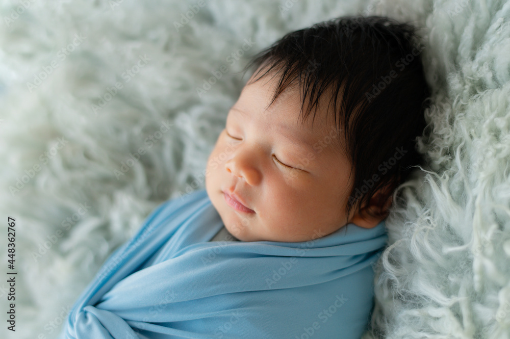 Cute  baby with blue sky  wrap lying on the  blanket.