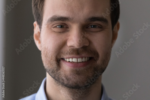 Close up cropped portrait of handsome young bearded guy face. Attractive millennial caucasian man successful businessman motivated worker looking at camera with perfect white toothy smile in good mood
