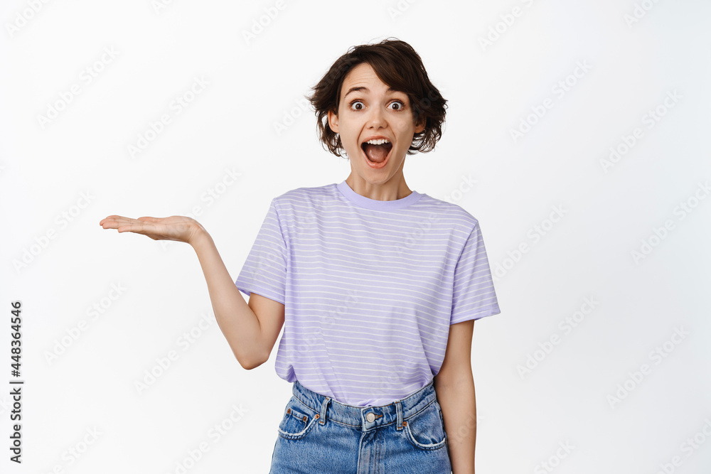 Happy young woman demonstrating smth on open hand, holding on palm, smiling excited, white background Happy young woman demonstrating smth on open hand, holding on palm, smiling excited, white background