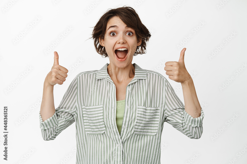 Excited girl smiling, showing thumbs up in approval, like and agree, satisfied with smth good, praise you, positive feedback, standing over white background Excited girl smiling, showing thumbs up in approval, like and agree, satisfied with smth good, praise you, positive feedback, standing over white background