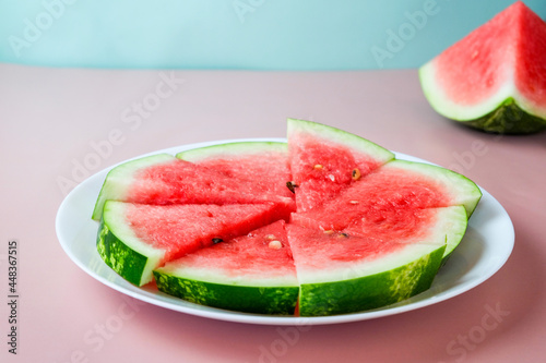 Pieces of watermelon on a round plate on a pink background. Top view, flat lay. Ripe watermelon slices. Vegetarian food. Place for text