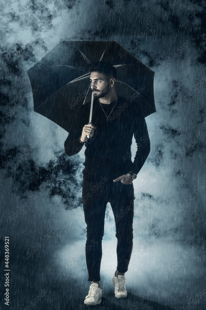 Young man under an umbrella, with rain and fog around Young man under an umbrella, with rain and fog around