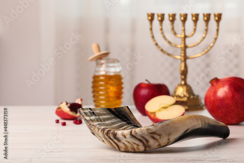 Shofar and other Rosh Hashanah holiday attributes on white wooden table indoors photo