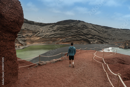young man walks down the path towards the green puddle. The Gulf. Yaiza. Canary Islands photo