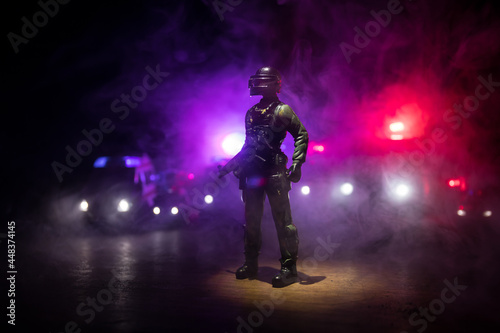 Fototapeta Naklejka Na Ścianę i Meble -  Anti-riot police give signal to be ready. Government power concept. Police in action. Smoke on a dark background with lights. Blue red flashing sirens. Dictatorship power