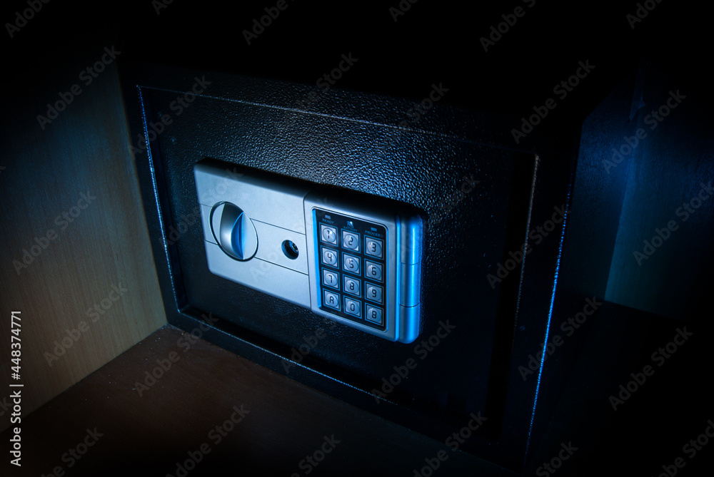 Small modern safe on shelf in dark. Small safe box close up in low key light Small modern safe on shelf in dark. Small safe box close up in low key light