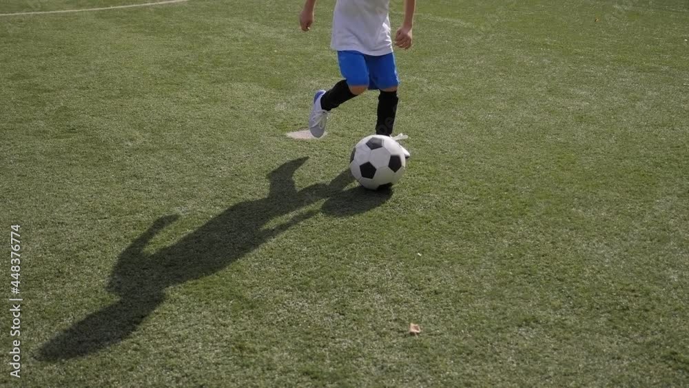 A little boy trains on the football field, practicing dribbling and feints. A little boy trains on the football field, practicing dribbling and feints.
