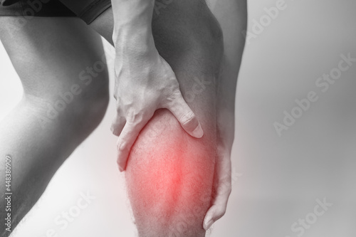 adult male with his muscle pain on gray background. Elderly man having leg ache due to Calf muscle pull. Sports injuries and medical concept © Jo Panuwat D
