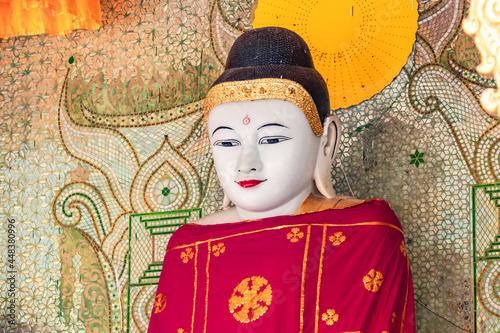 Fotografie Eine reich verzierte Buddha-Statue mit rotem Gewand in einem Tempel der Shwedago