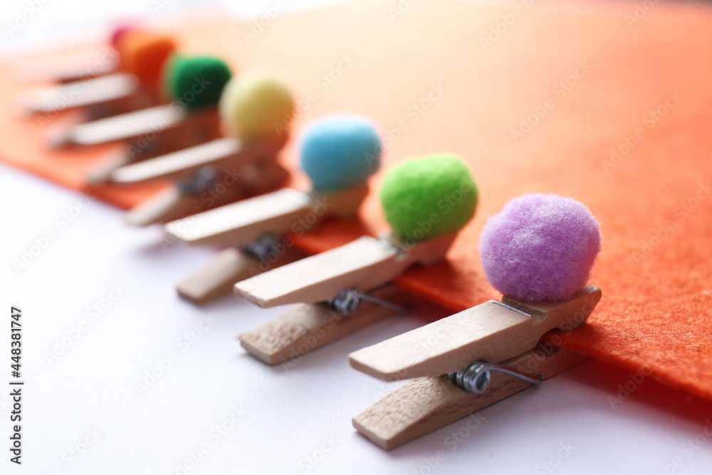 Sheet of orange felt with clothespins and small soft balls on white background, closeup Sheet of orange felt with clothespins and small soft balls on white background, closeup