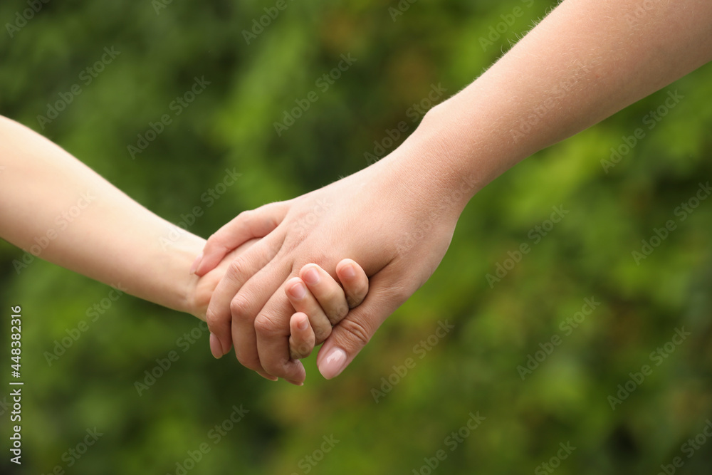 Woman and child holding hands outdoors, closeup Woman and child holding hands outdoors, closeup