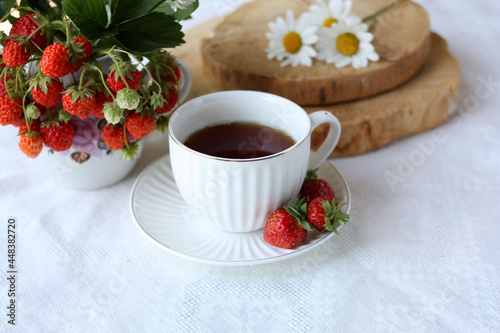 A cup of tea on the background of a bouquet of strawberries.