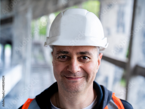 The man removes the protective mask from his face to symbolize the end of the pandemic. Portrait of a male Builder in a construction helmet and a medical antiviral mask.