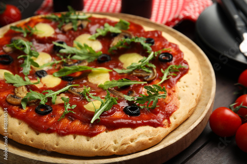 Pita pizza with cheese  olives  mushrooms and arugula on wooden table  closeup