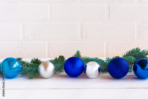 Christmas composition with blue and silfer baubles and fir tree brances on white brick wall background with copy space for text