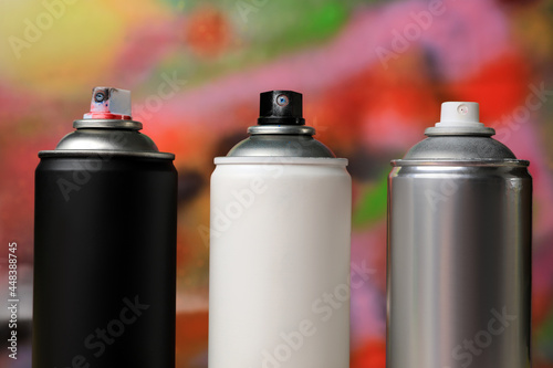 Cans of different graffiti spray paints on color background, closeup