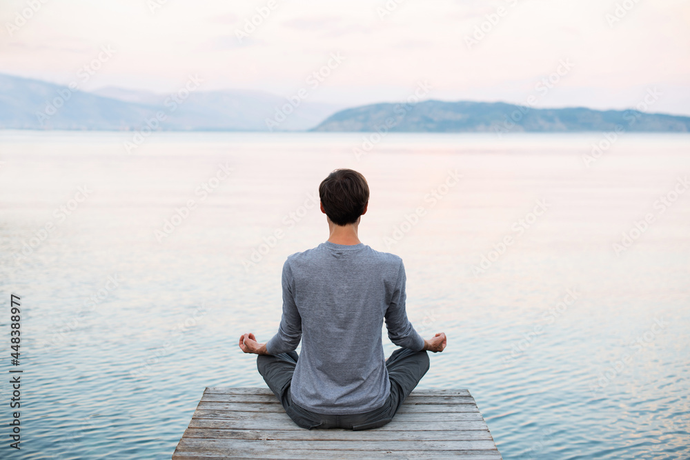 Young man practicing yoga and meditate near the sea at sunrise, Harmony, meditation, healthy lifestyle, travel and mindfulness concept