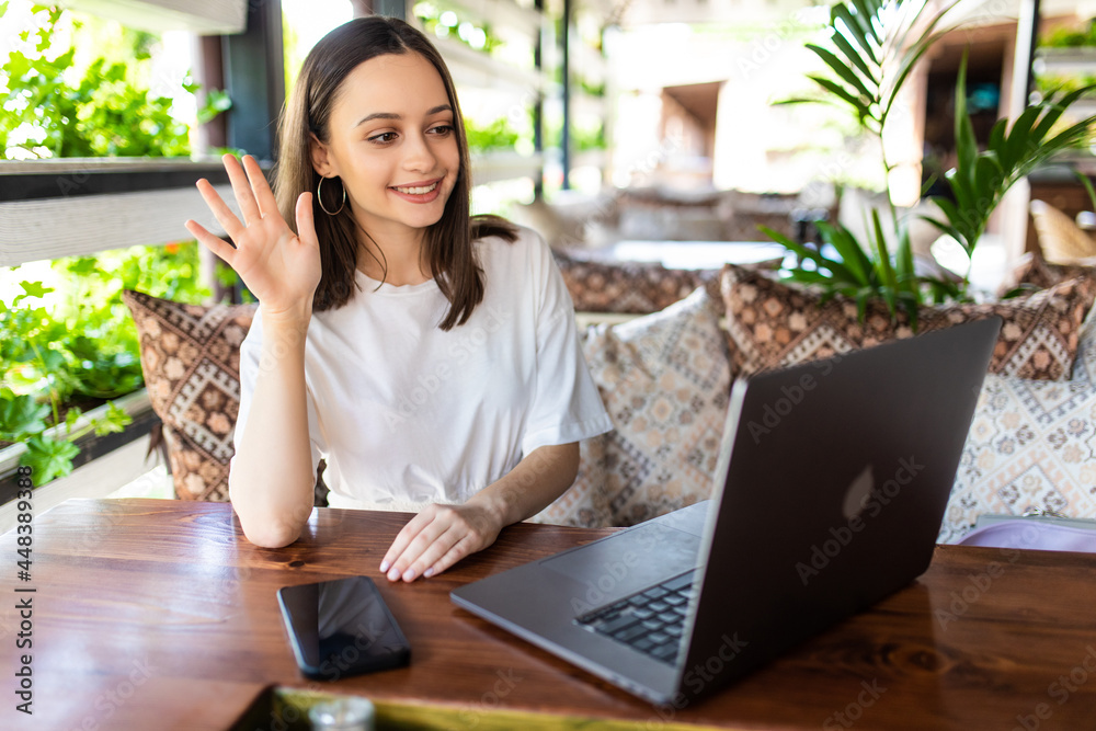 Young woman using laptop and making video call in cafe. Young woman using laptop and making video call in cafe.