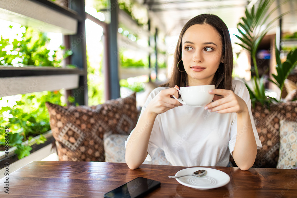 Smiling woman in a good mood with cup of coffee sitting in cafe. Smiling woman in a good mood with cup of coffee sitting in cafe.
