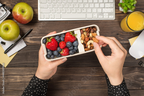 Photography First person top view photo of woman's hands holding lunchbox with healthy meal