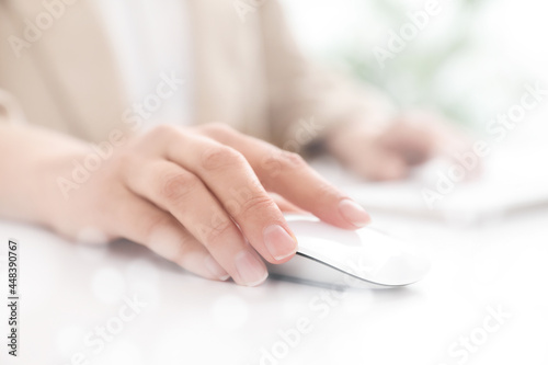 Woman using computer mouse at desk, closeup