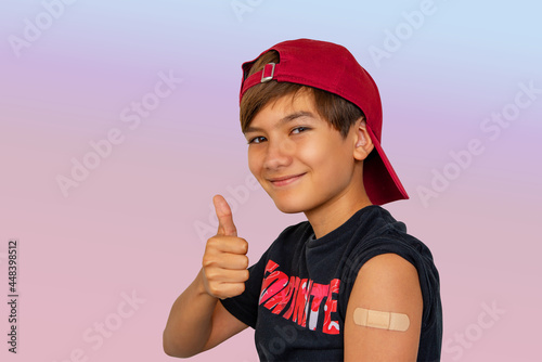 Portrait Of boy11-12 years old boy got HPV vaccine to prevents infection from the strains of HPV cancer. BoSy with Vaccinated Arm With Sticking Patch On the Shoulder After Getting Shot And Thumb Up.  photo