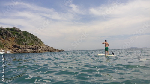 men stand-up paddle sea water beach