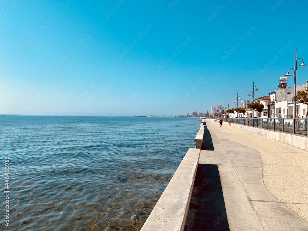 Coastal line with concrete pavement and houses in distance