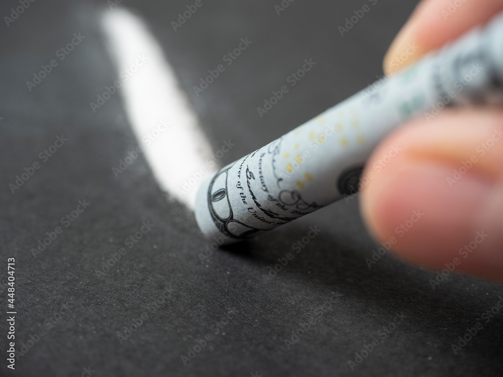 White Powder Line close-up of a hundred-dollar bill rolled into a tube above a line of ...