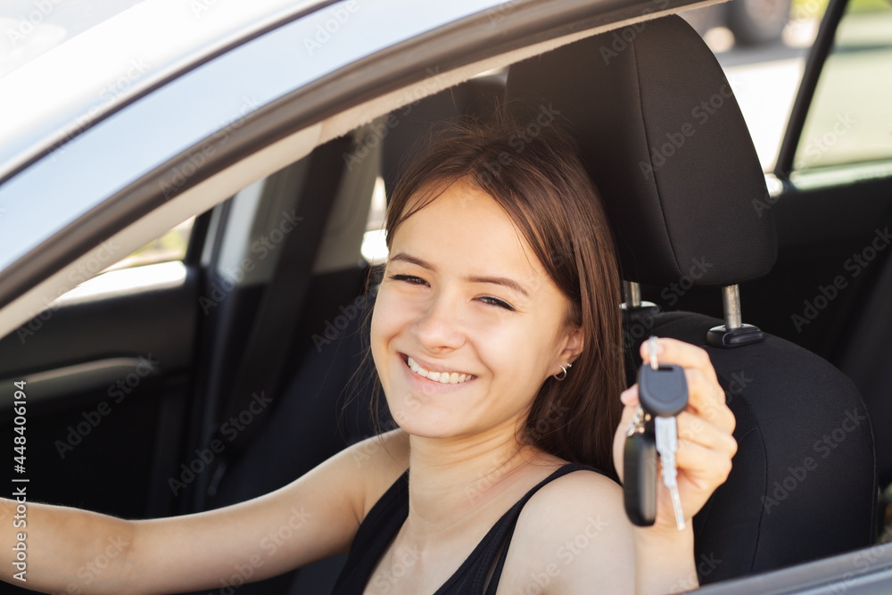 teenager in car,girl has received a driver's license,young woman is happy to be able to drive a car
