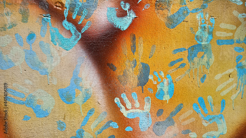 Handprints and dripping paint on the textured background of an old painted wall.
