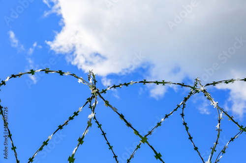 Barbed wire and blue sky as symbols of injustice and freedom