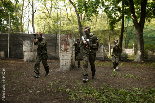 Warriors in camouflage and masks playing paintball