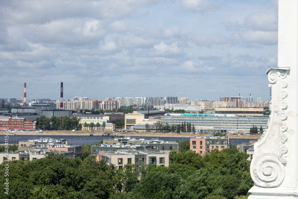 Panoramic top view of the city with roofs of houses and green foliage of trees on a cloudy summer day in St. Petersburg Russia
