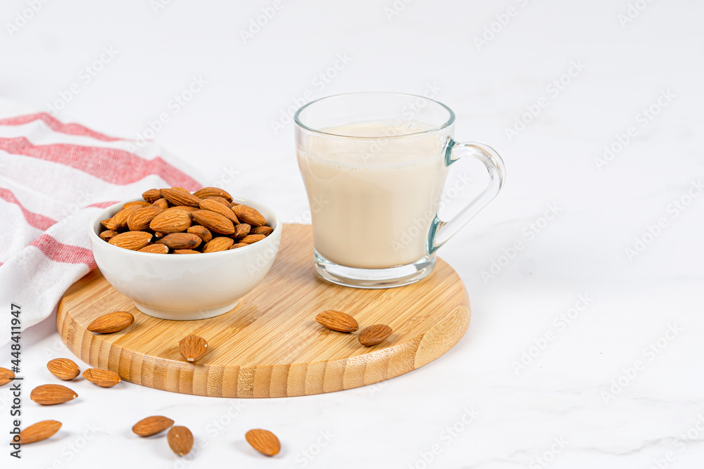 Almond milk in a glass with almond on a wooden table