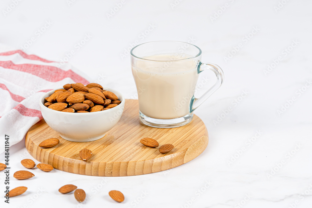 Almond milk in a glass with almond on a wooden table Almond milk in a glass with almond on a wooden table