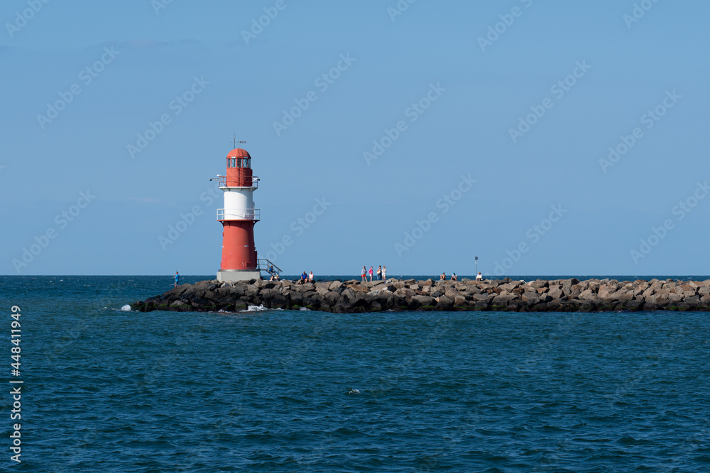 Red and white lighthouse on the Baltic Sea (inland sea) with cloudless sky and bright sunshine