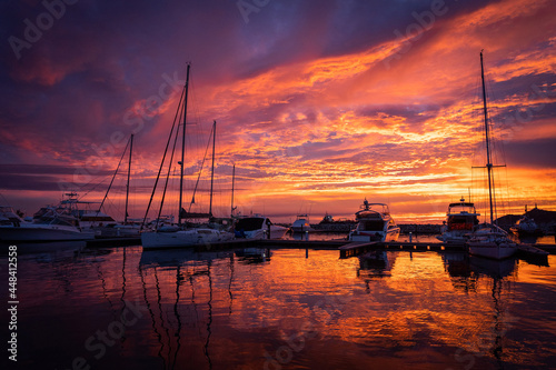 Dramatic sunset over sailboats in the calm water of marina. Travel and adventure concept 