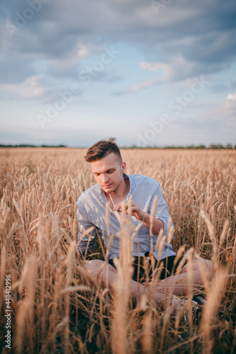 a village guy is sitting in a field in a white shirt and enjoying nature