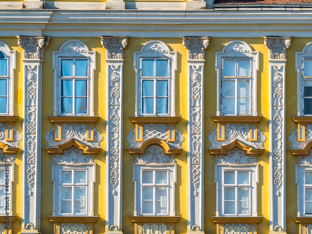 Facade of or front view of a beautiful old building in timisoara, Romania .Architectural detail of two yellow colored wooden framed windows