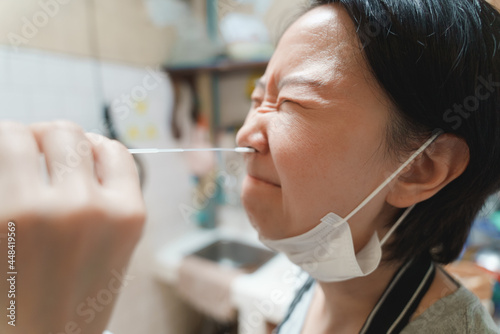 Asian woman look painful while doing swab test at home by her self.