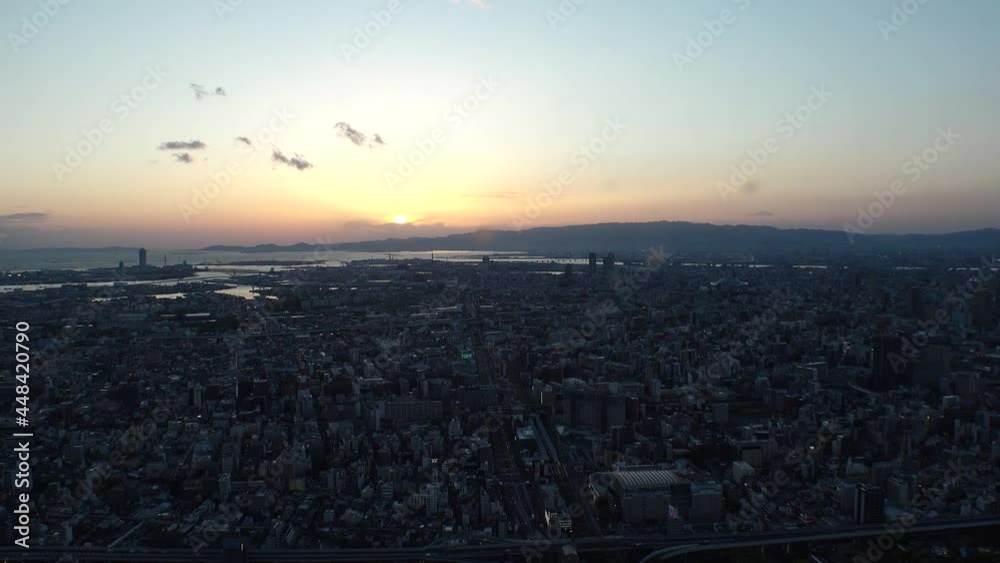 OSAKA, JAPAN : Aerial high angle sunset view of CITYSCAPE of OSAKA. View of buildings and street traffic around Osaka bay and Kobe port. Long time lapse wide view shot, dusk to night. OSAKA, JAPAN : Aerial high angle sunset view of CITYSCAPE of OSAKA. View of buildings and street traffic around Osaka bay and Kobe port. Long time lapse wide view shot, dusk to night.