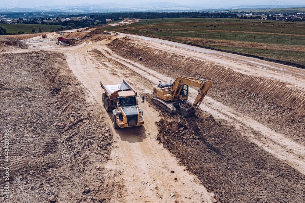 Aerial drone view of excavator and tipper truck at the construction site.
