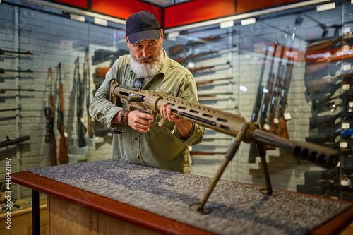 Bearded man reload powerful rifle in gun store