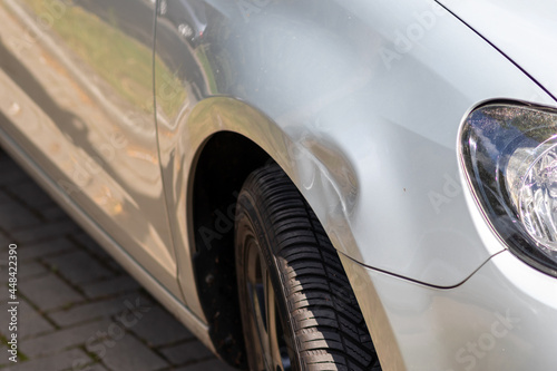Dented car wing and fender with scratches and bumps after crash and car accident with hit-and-run driving and absconding shows need for car insurance and safety protection and mechanics garage service