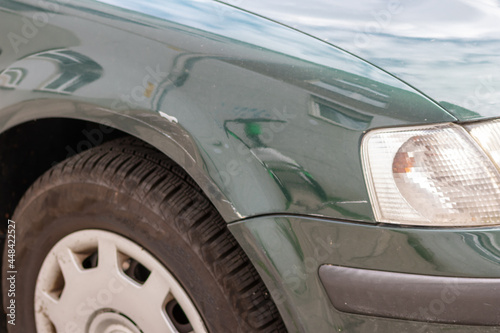 Dented car wing and fender with scratches and bumps after crash and car accident with hit-and-run driving and absconding shows need for car insurance and safety protection and mechanics garage service