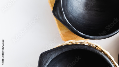 black clay dishes in a wooden basket, very traditional to serve food, used in Colombia. on white background